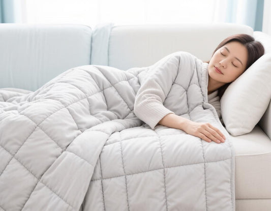 Woman sleeping peacefully on a sofa under a quilted weighted blanket