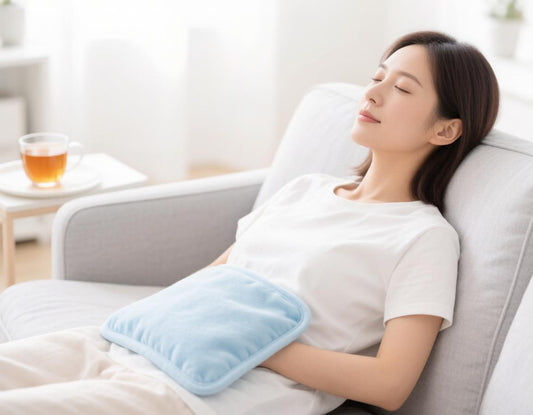 Woman resting on a sofa with a heating pad on her lower abdomen for period cramps